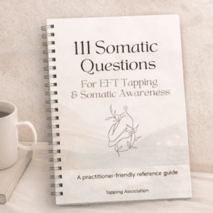 A spiral-bound "111 Somatic Questions for EFT Tapping – Practitioner Reference Guide (Printable PDF)" rests on a light surface beside a cup.